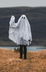 Image of a person dressed as a ghost, waving hello